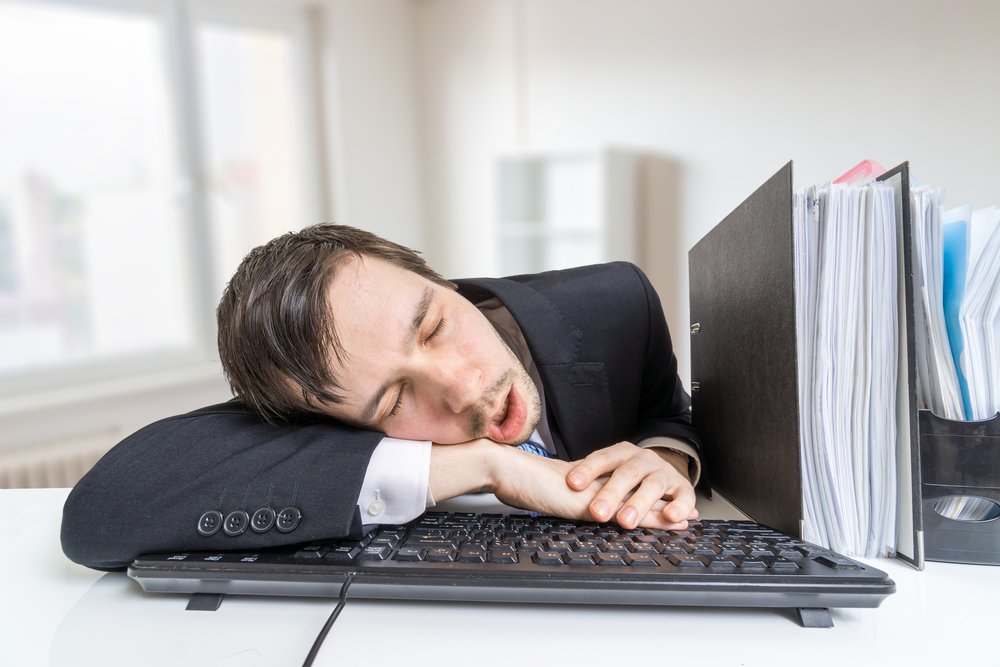 Tired overworked man is sleeping on keyboard in office at work.